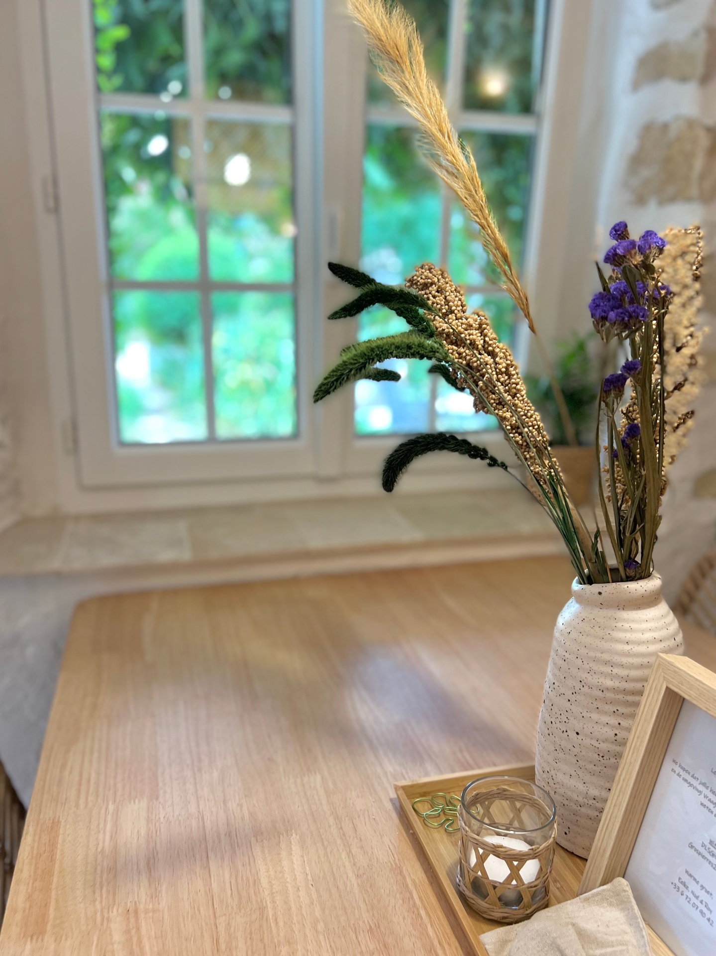 Eettafel met droogboeket bij het raam met uitzicht op de tuin