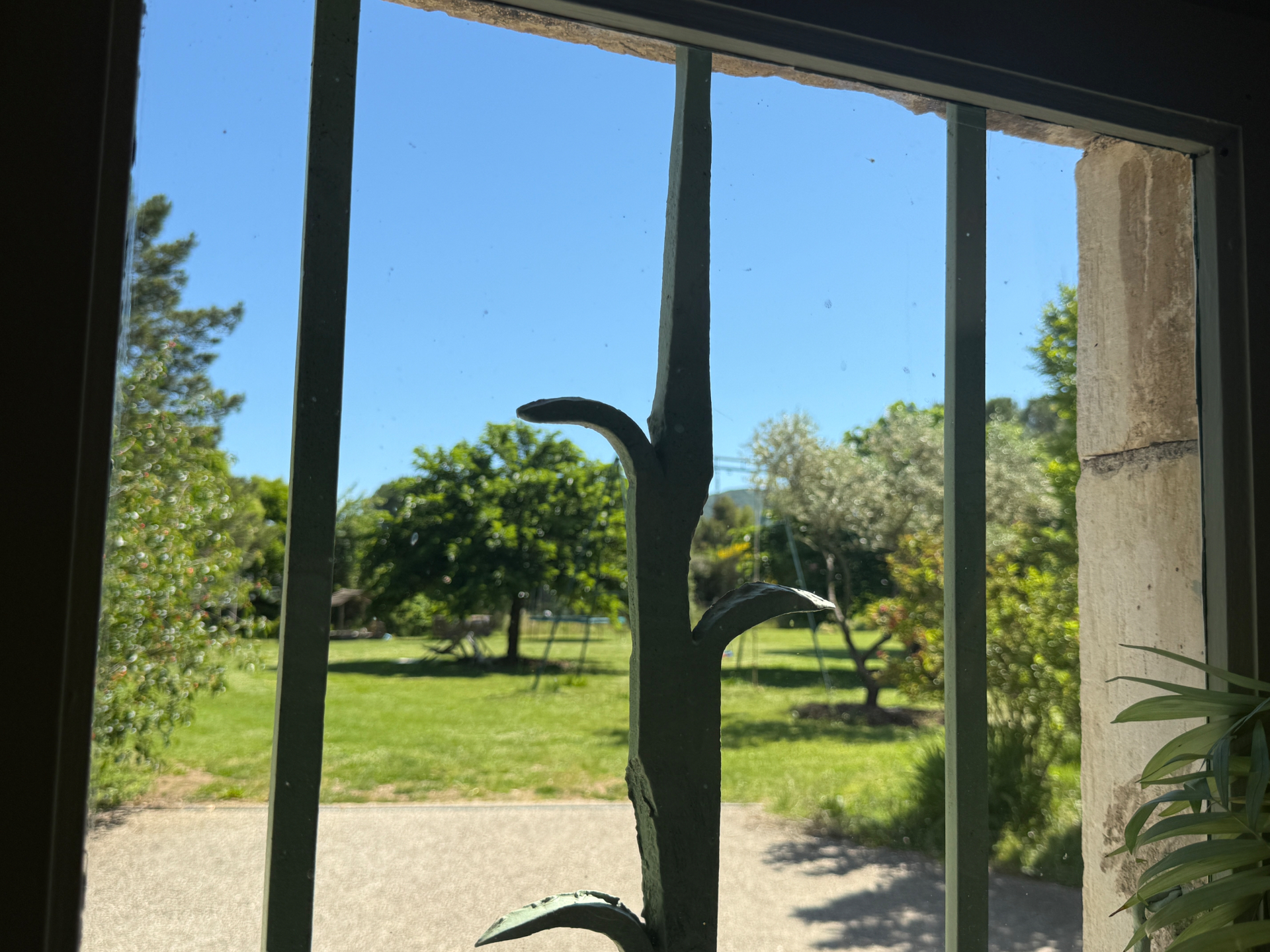 Uitzicht door het smeedijzeren raam op de tuin